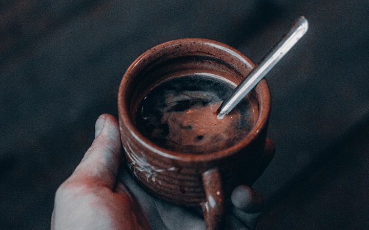 asse en terre cuite remplie de café chaud, cuillère posée à l'intérieur,